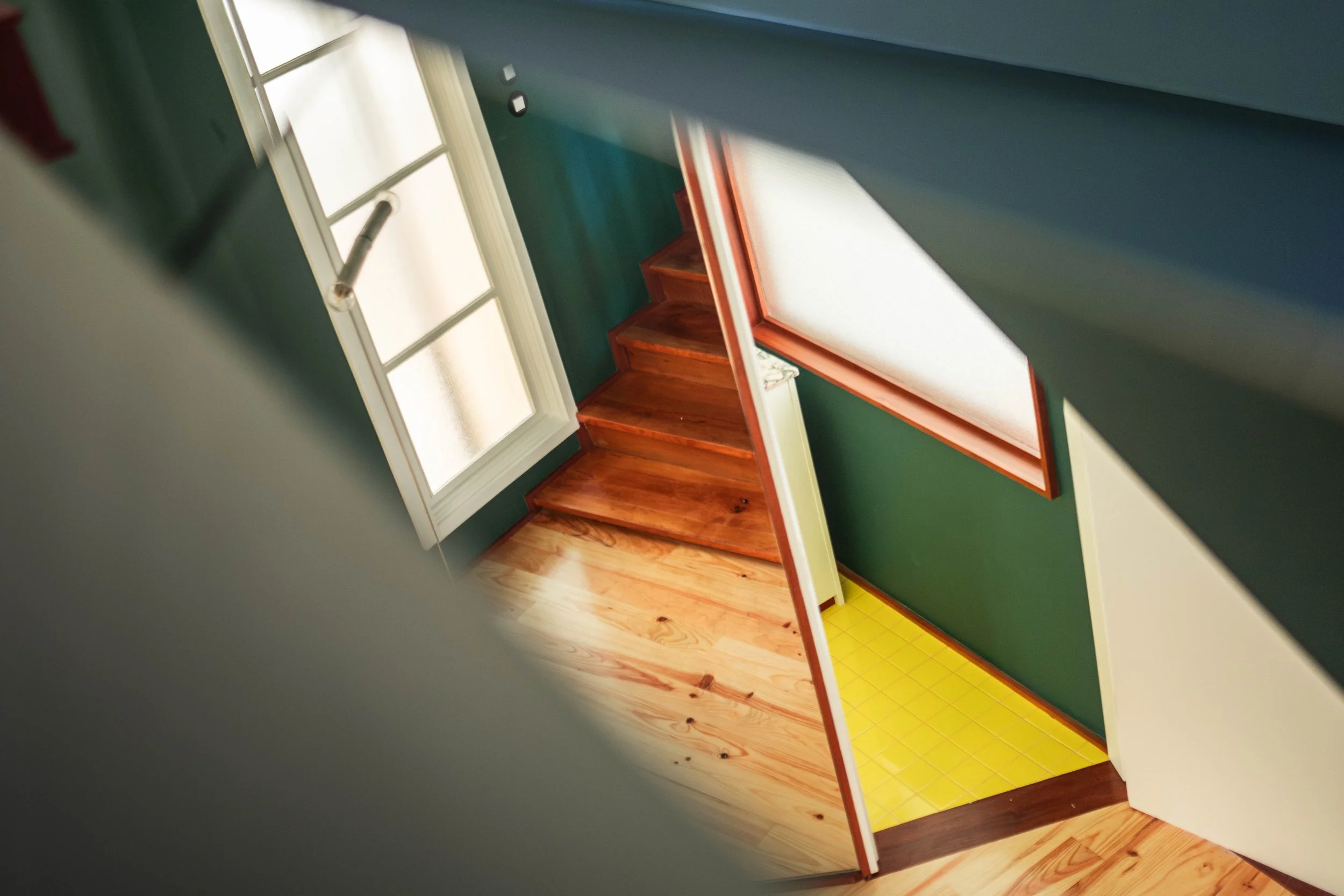 A wooden stair and green walls inside MAD House in Porto